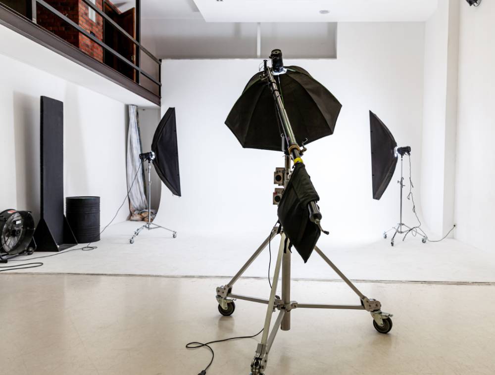 A well-lit photo studio with a white backdrop and various lights with filters, showcasing professional photography equipment.